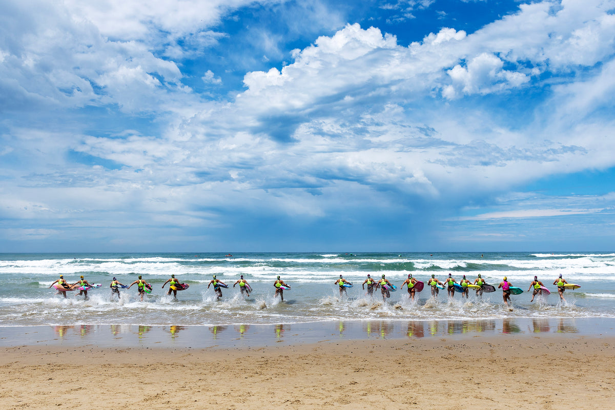 Board paddlers sprint into the surf at the start of a Shaw and Partners World Ocean Series race
